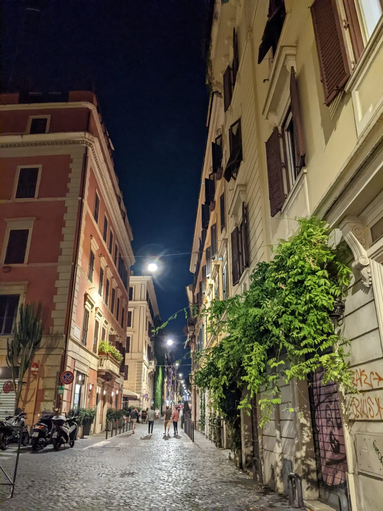 Rue pavée éclairée la nuit et ses scooters garés