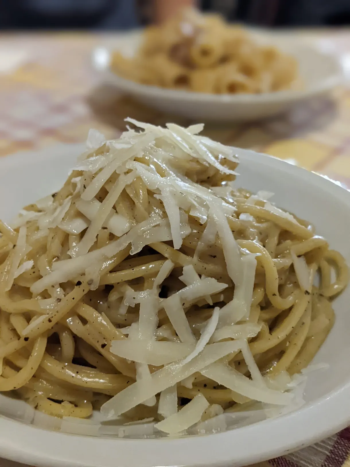 Pâtes nappées de pecorino râpé dans une assiette creuse
