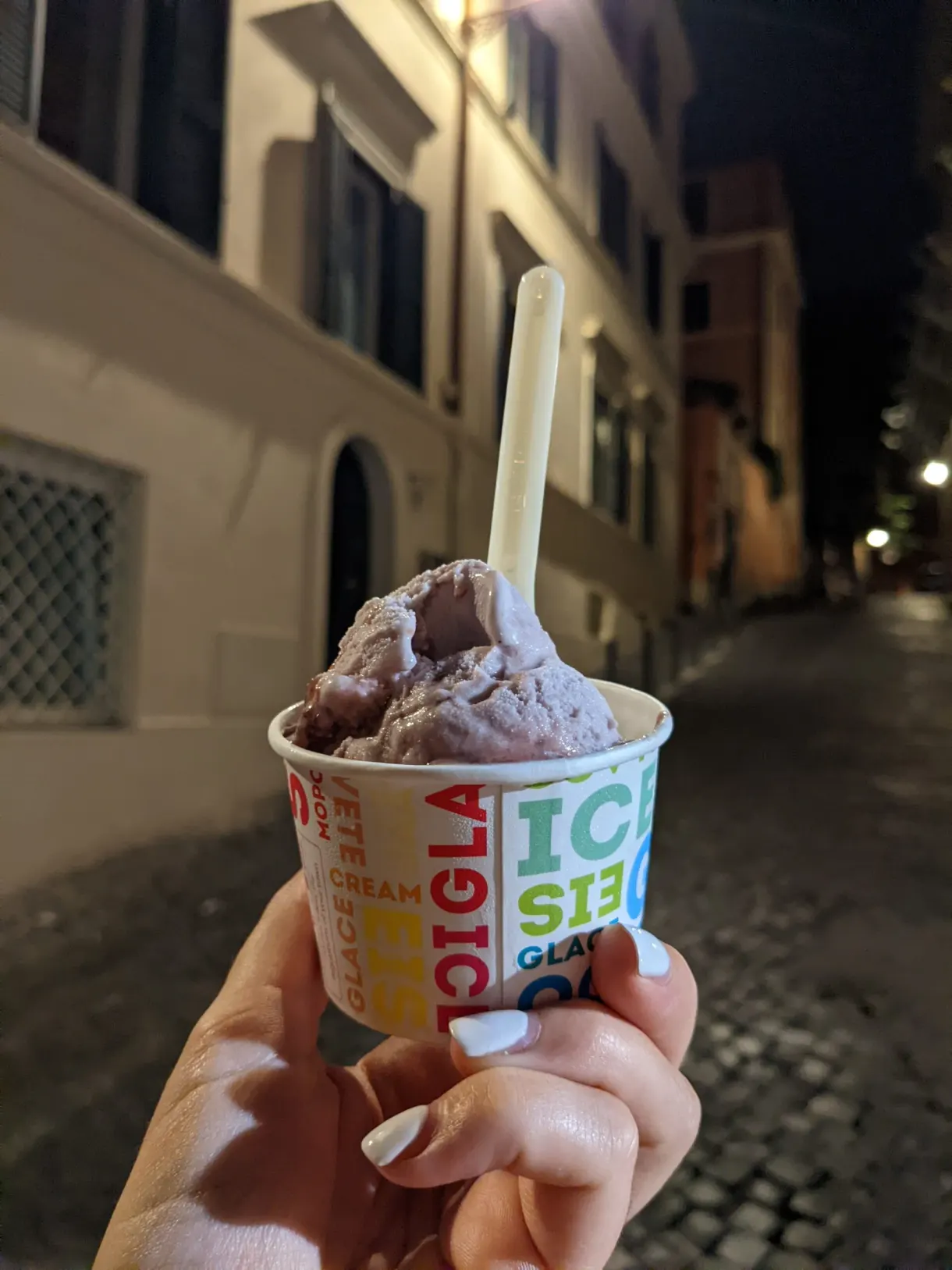Glace au chocolat tenue dans une ruelle pavée la nuit