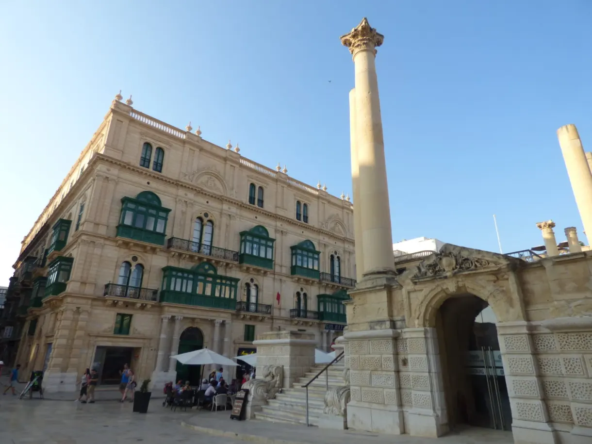 Palais aux balcons verts et colonne de pierre sur la place