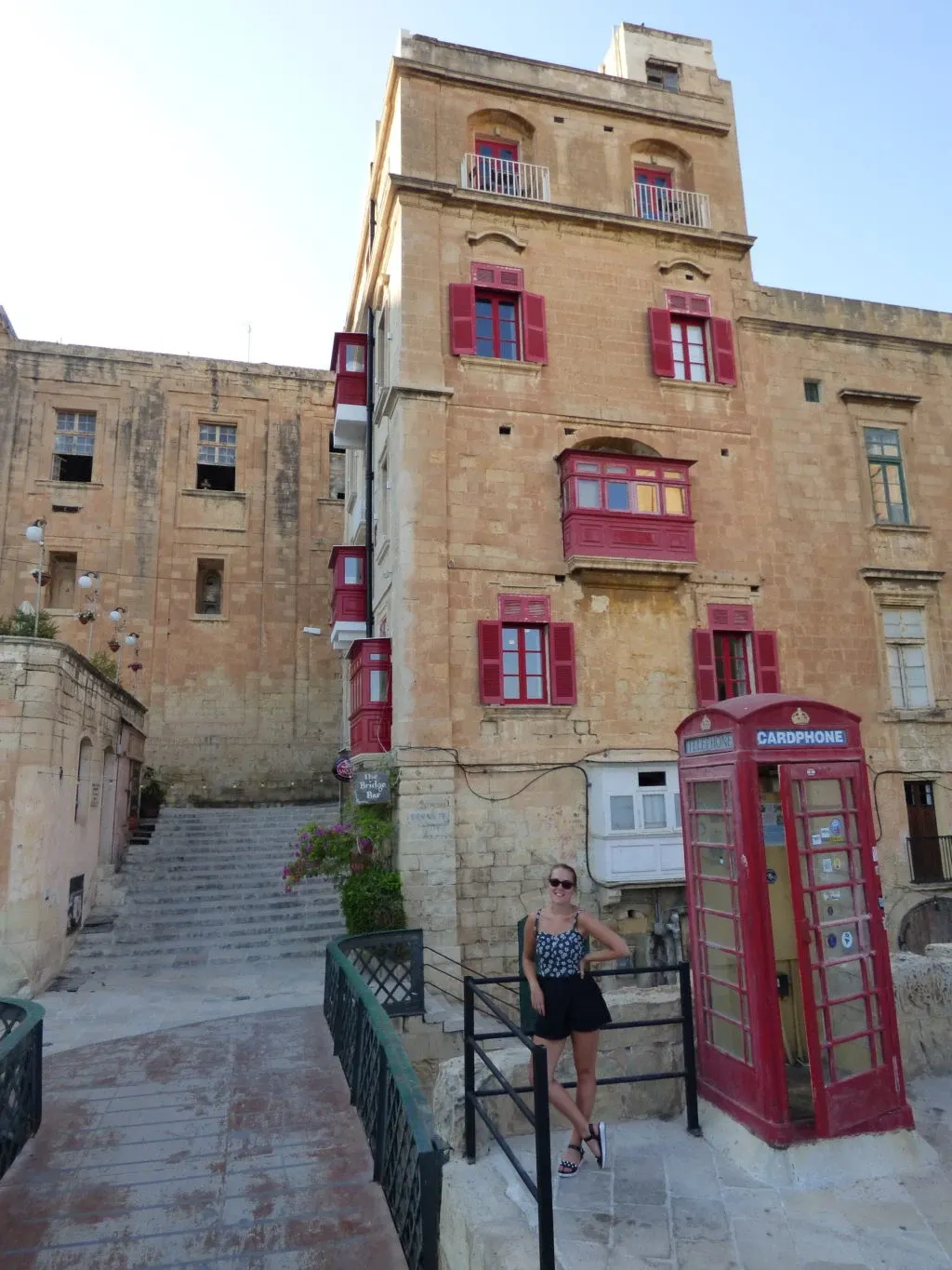 Femme près d'une cabine téléphonique rouge en haut d'un escalier