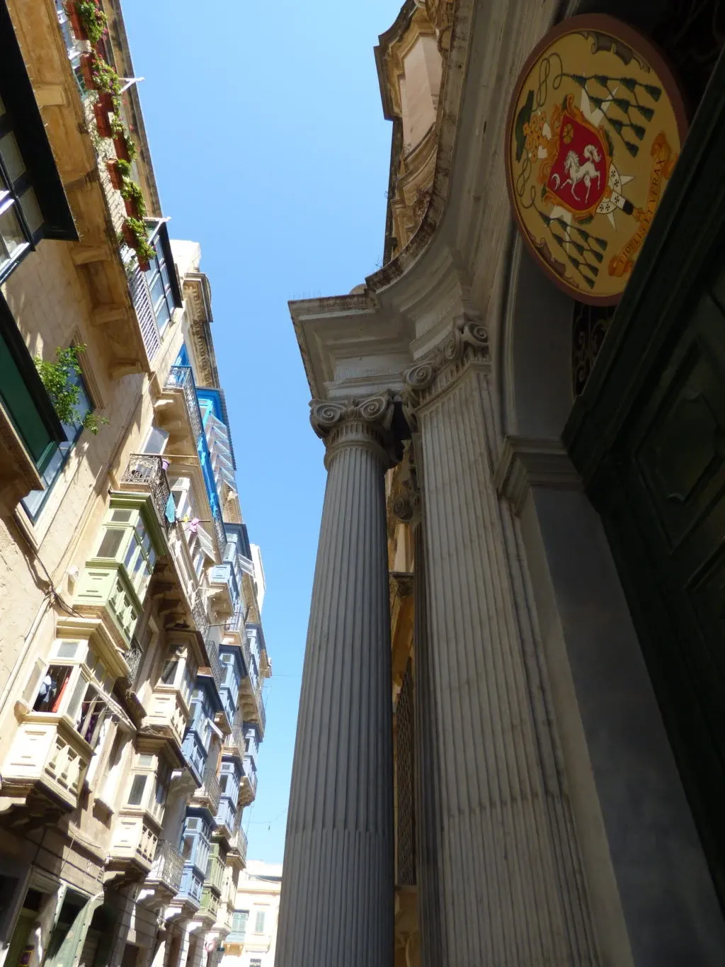 Colonne et blason sculpté en contre-plongée entre les façades