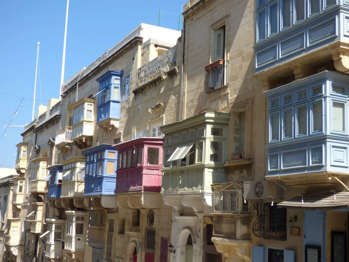 Alignement de balcons colorés sur une façade de pierre blonde
