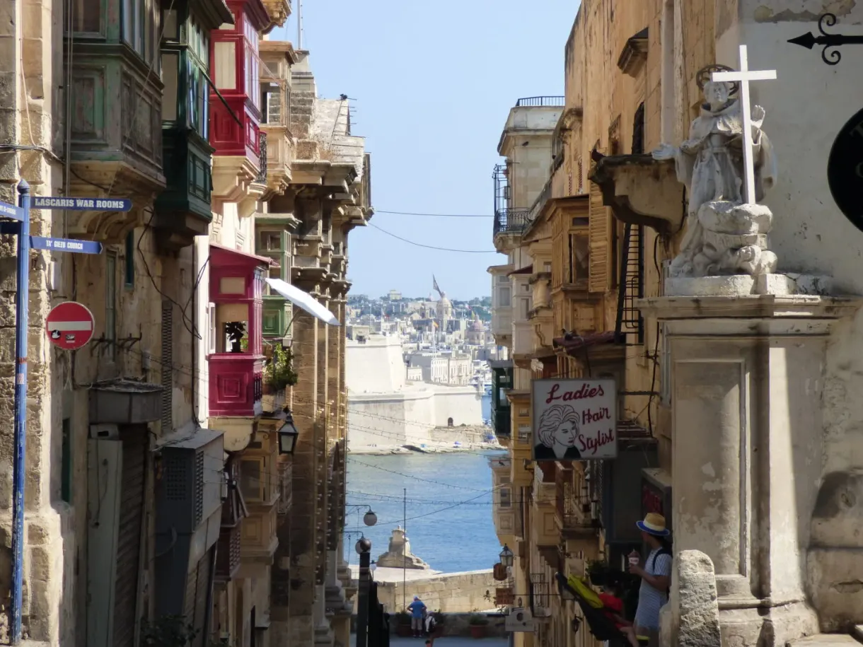 Rue en pente vers le port, croix de pierre au premier plan
