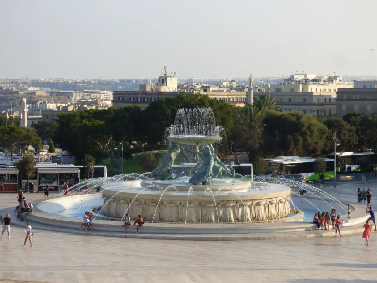 Bassin circulaire de la fontaine et passants sur l'esplanade