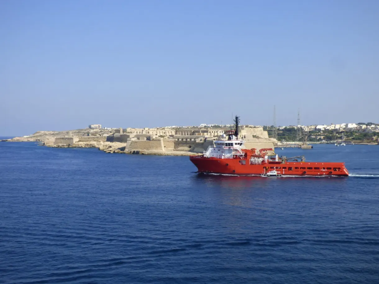 Navire de ravitaillement rouge passant devant les fortifications