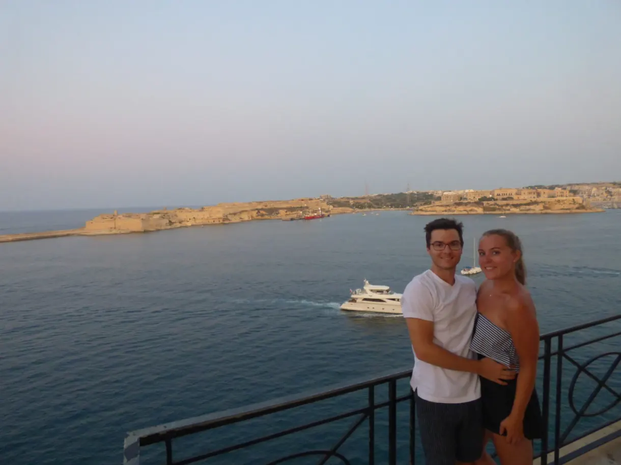 Couple posant devant le port au coucher du soleil