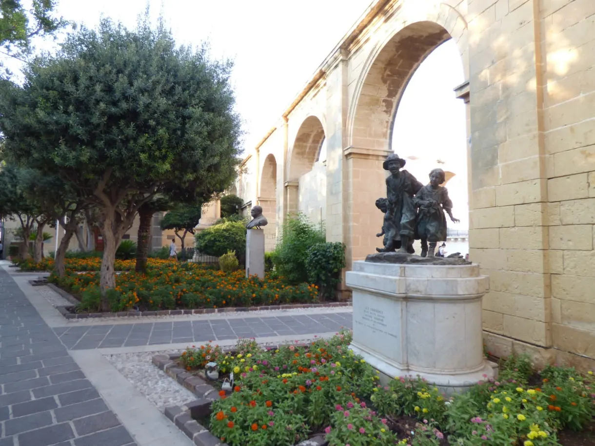 Statue de bronze et massifs fleuris sous les arcades
