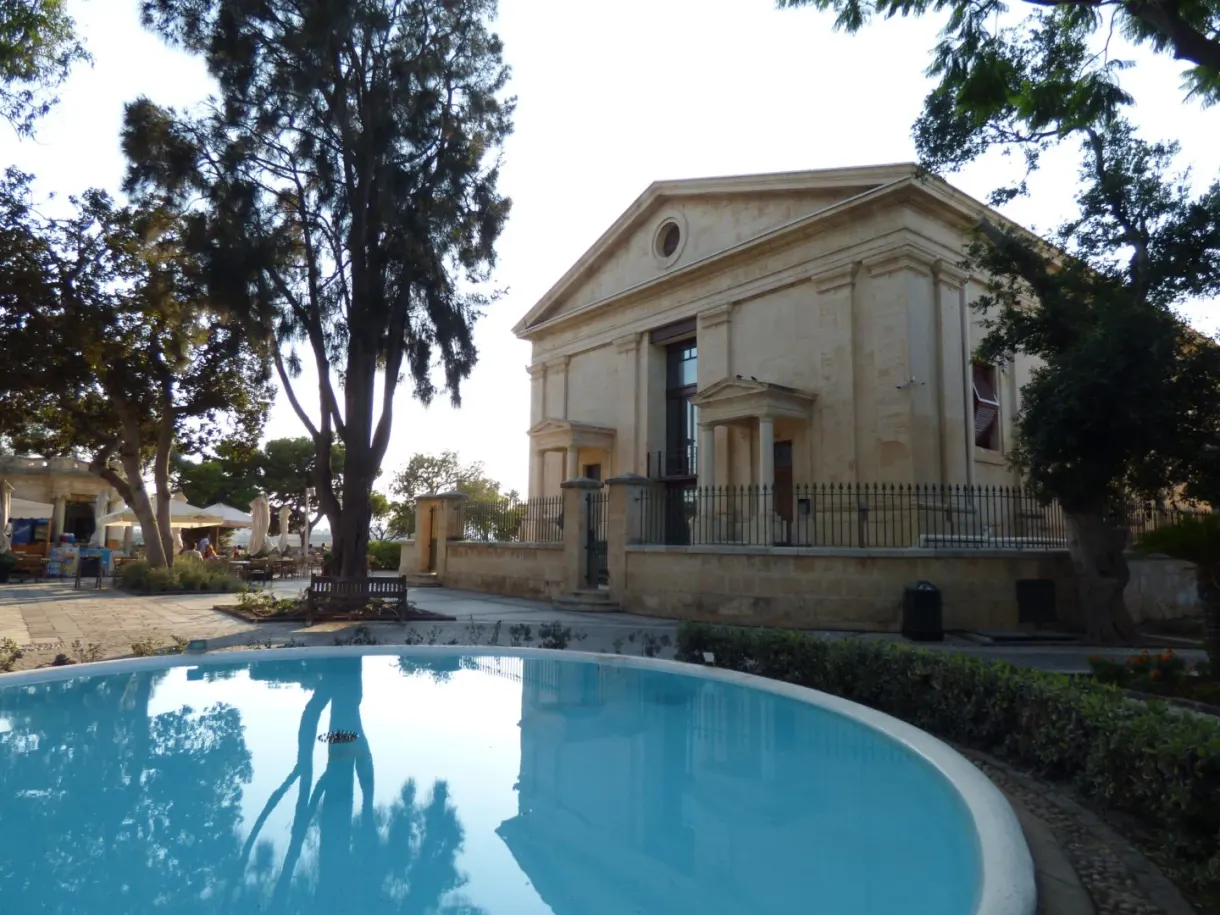 Bassin turquoise reflétant les arbres devant un temple néoclassique