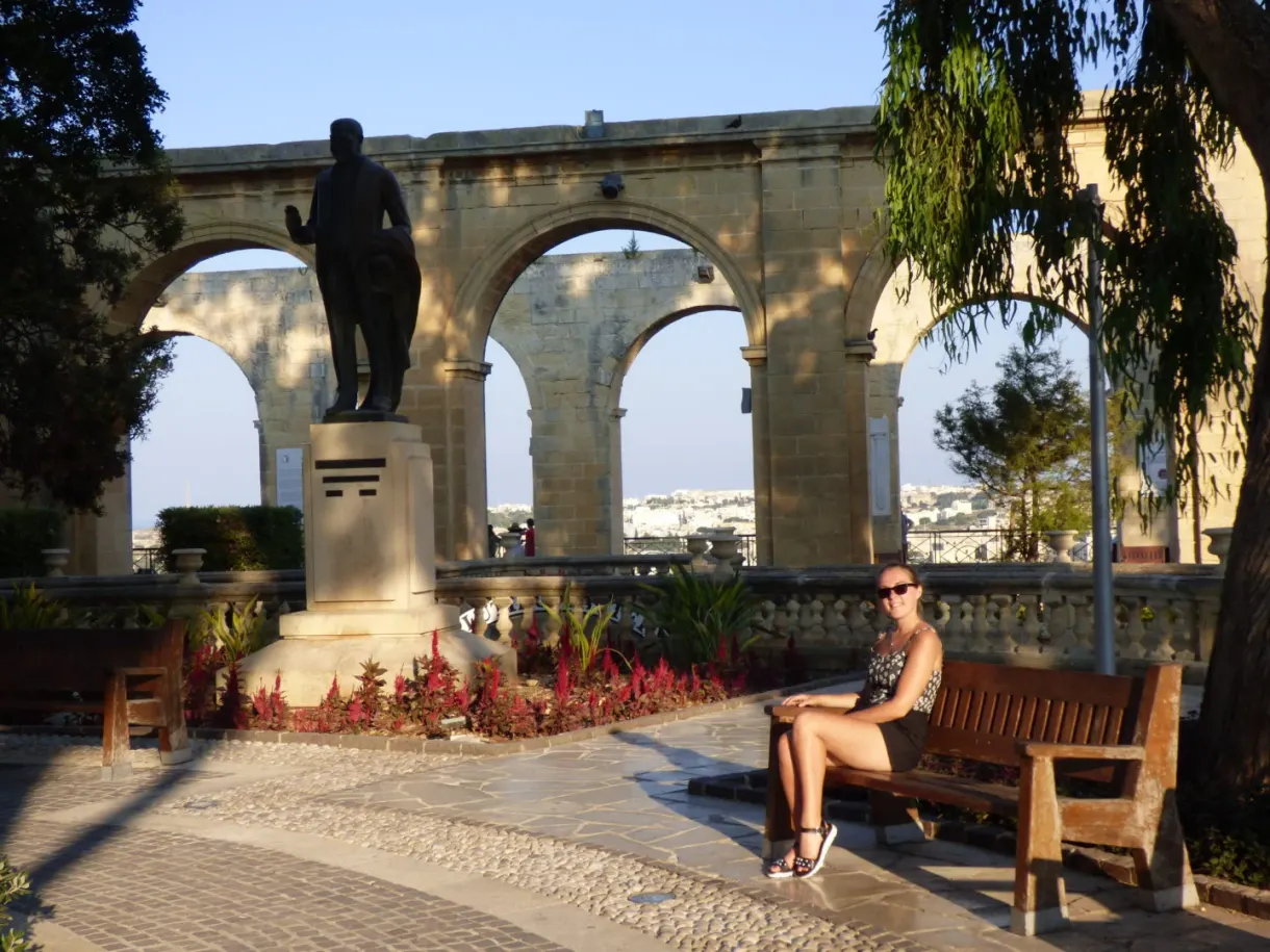 Femme assise sur un banc à l'ombre des arcades
