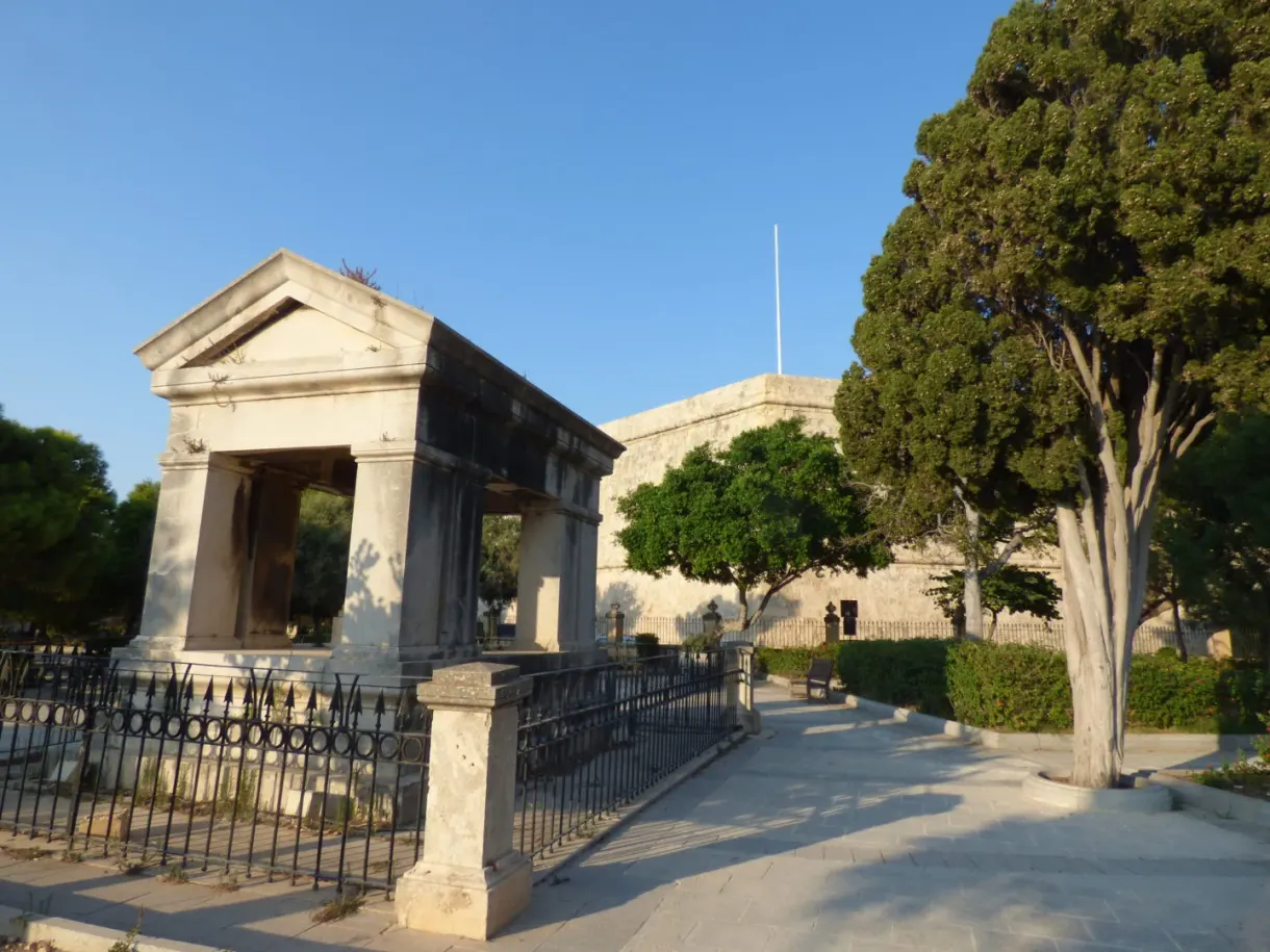 Monument néoclassique entouré d'une grille et de grands arbres