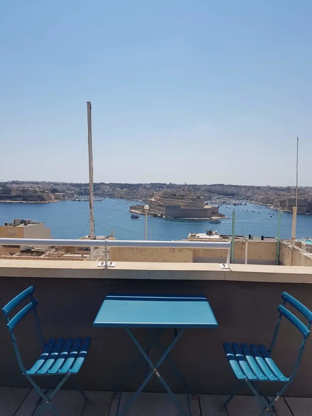 Table et chaises bleues sur la terrasse face au port