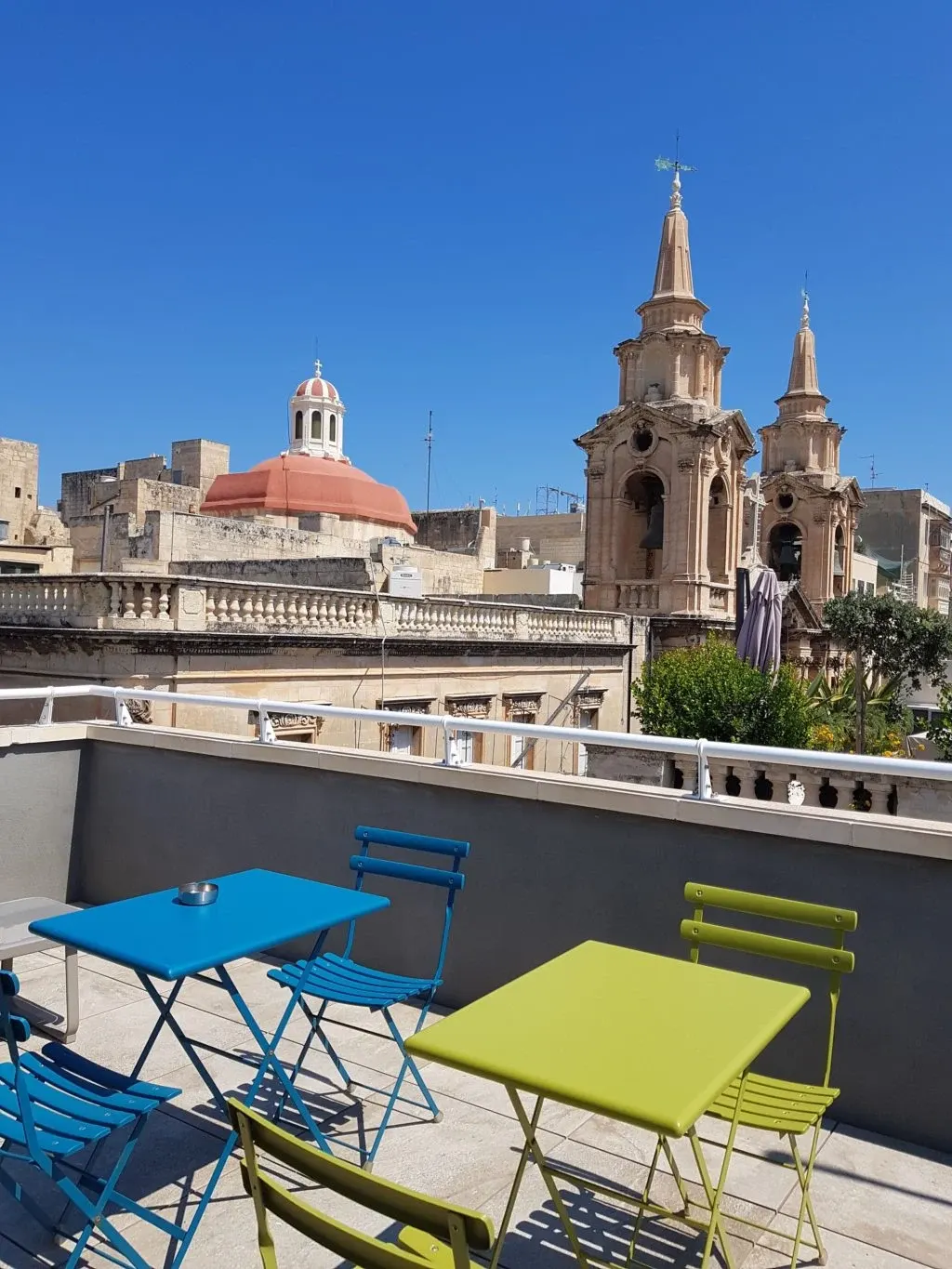 Chaises vertes et bleues devant les clochers de la ville