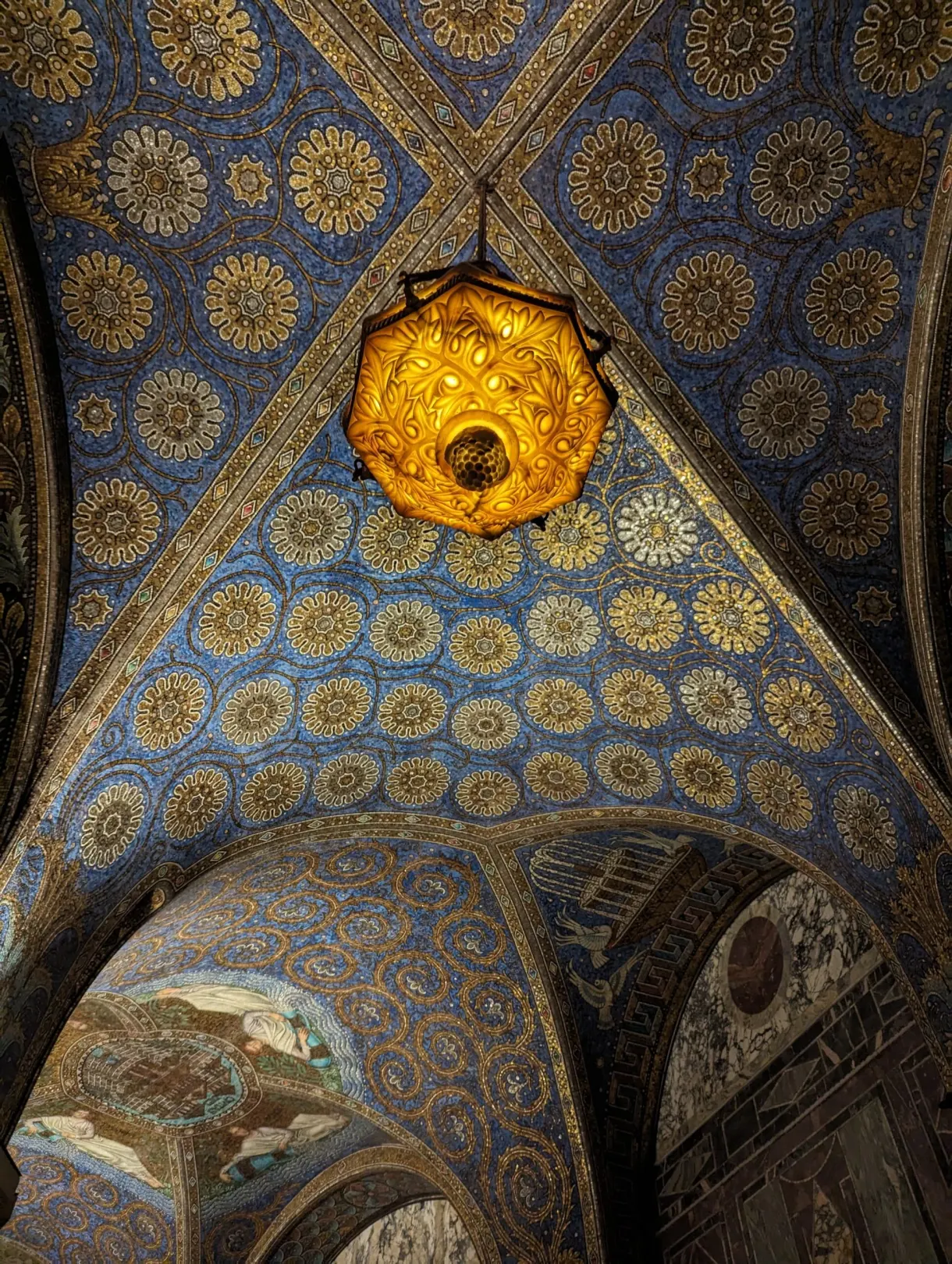 Lustre doré suspendu sous une voûte bleue semée de mosaïques