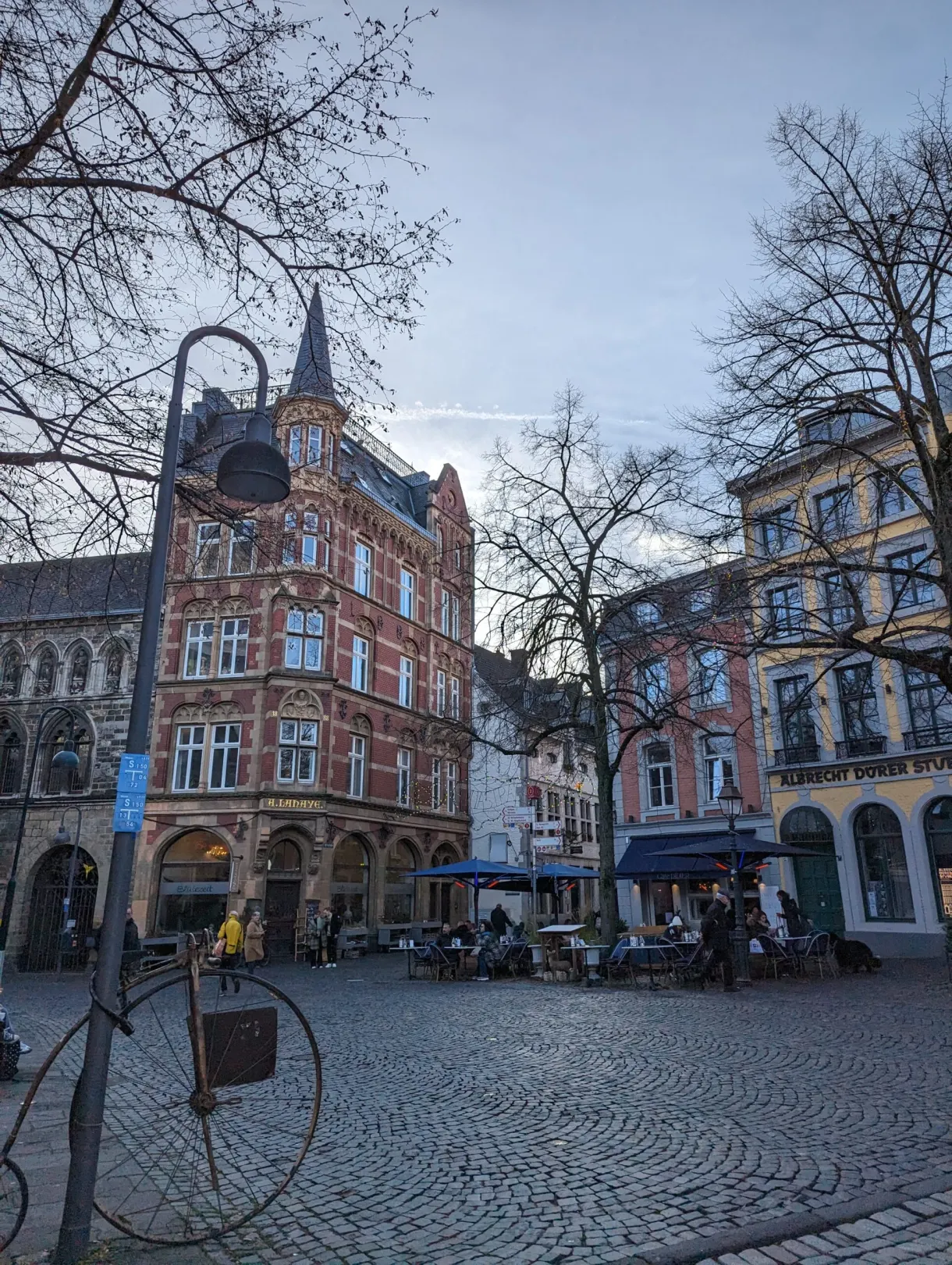 Place pavée bordée de maisons anciennes sous les arbres nus