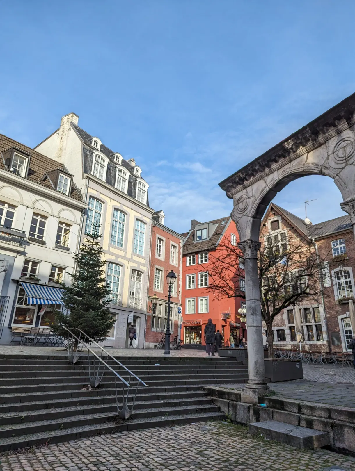 Arcades de pierre et façades colorées autour d'un sapin de Noël