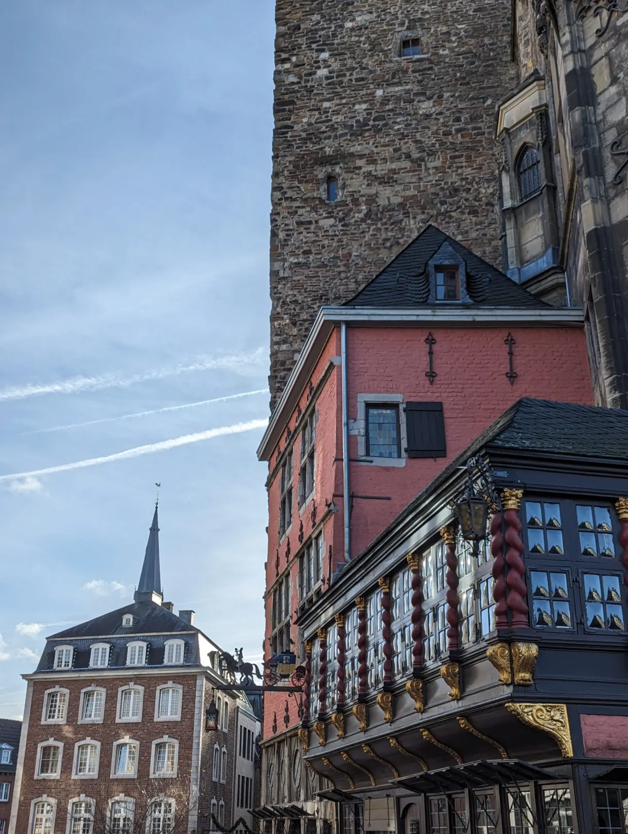 Balcon ouvragé et maisons colorées au pied d'une tour de pierre