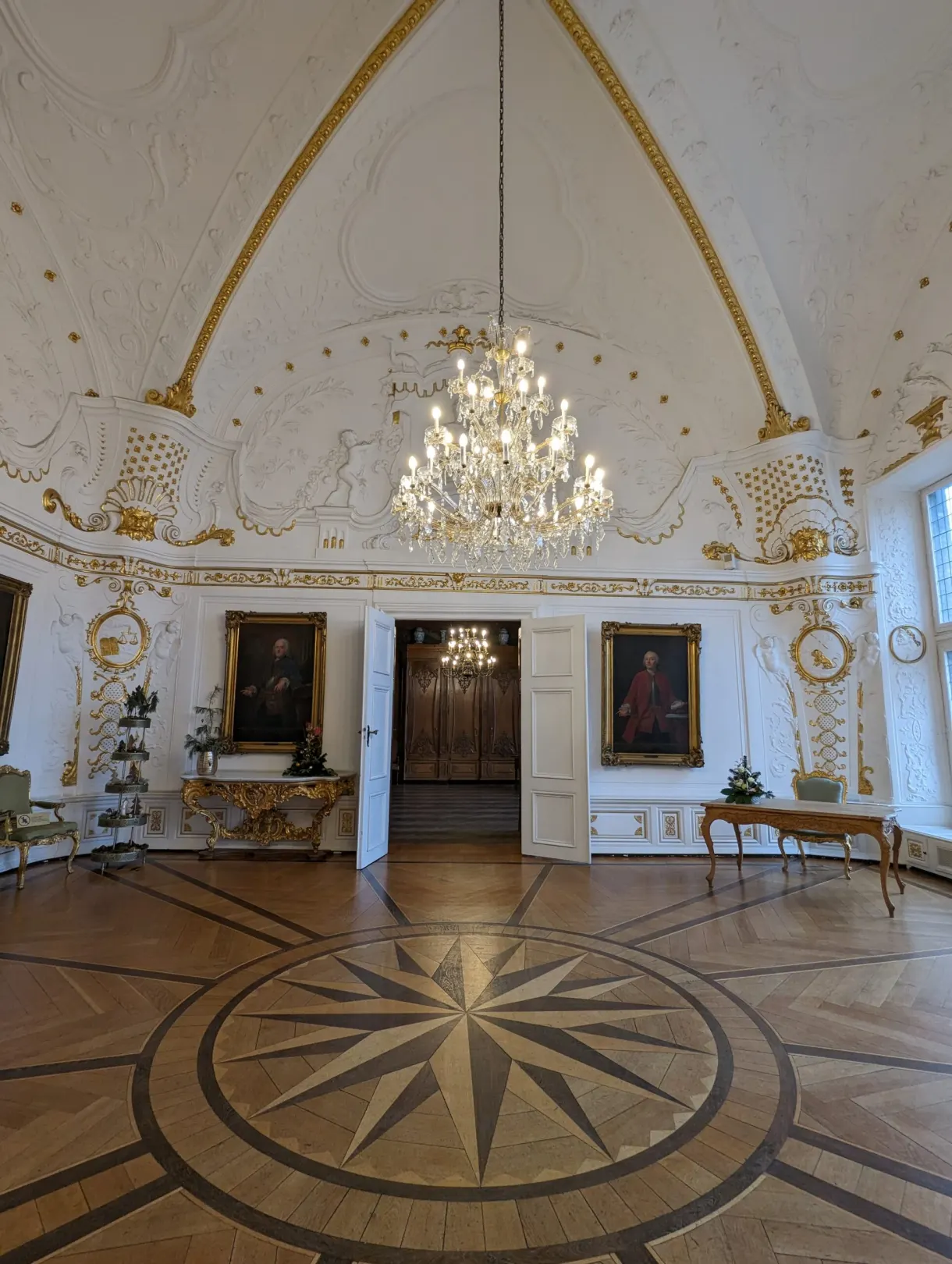 Rosace de parquet sous un lustre dans une salle blanche