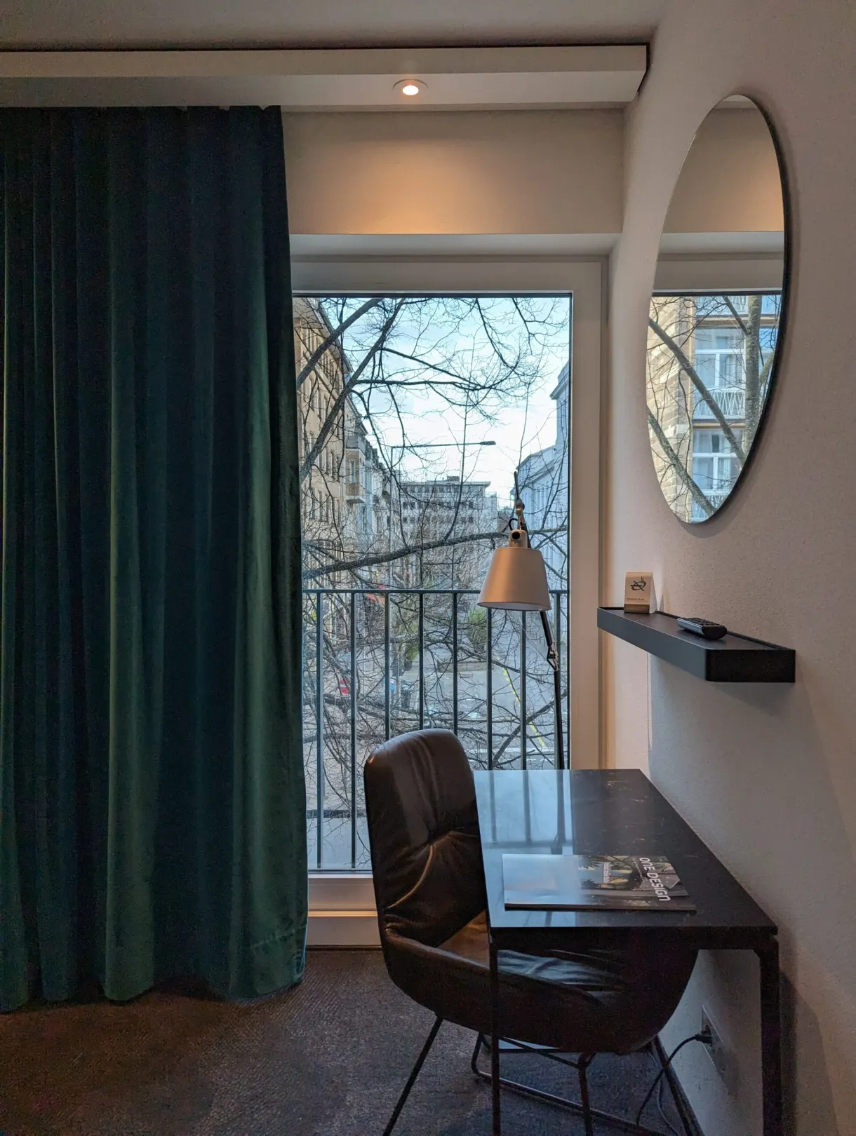 Coin bureau, miroir rond et fenêtre sur les toits voisins