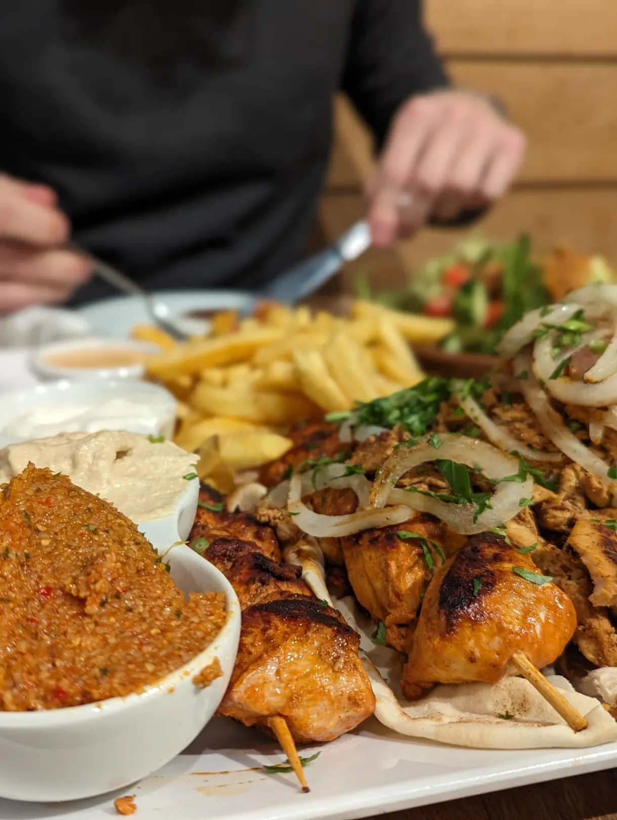 Brochettes grillées, frites et houmous partagés à table