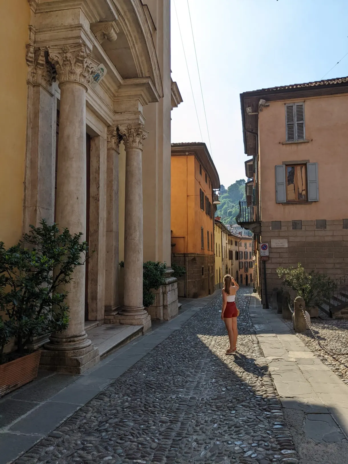 Passante en tenue rouge dans une rue bordée de colonnes