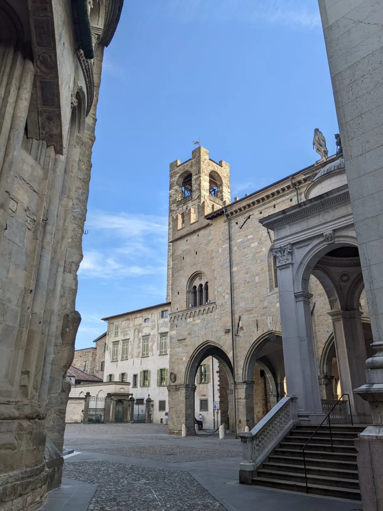Tour crénelée aperçue depuis les arcades d'une place
