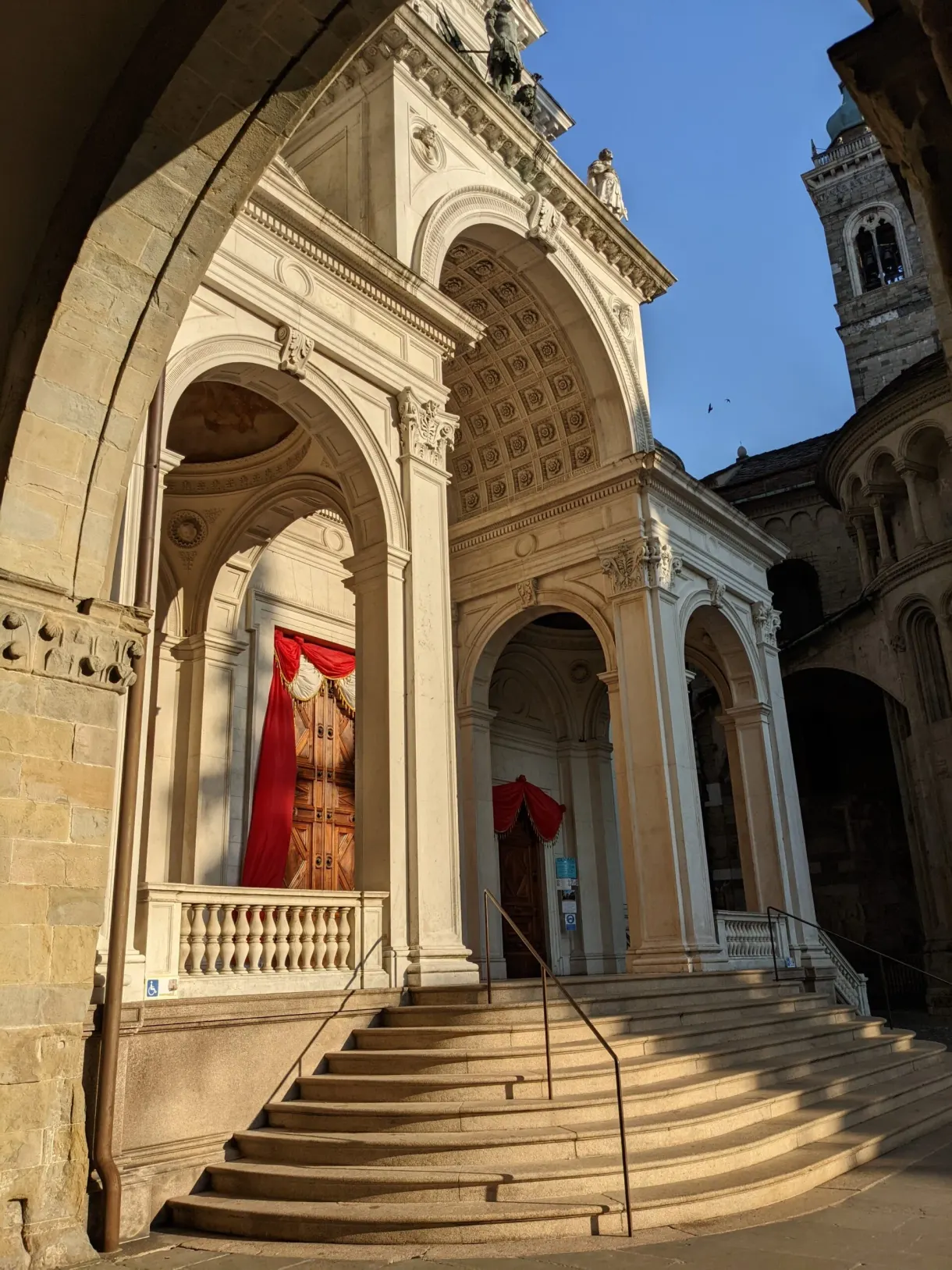 Porche à colonnes et escalier menant à une tenture rouge