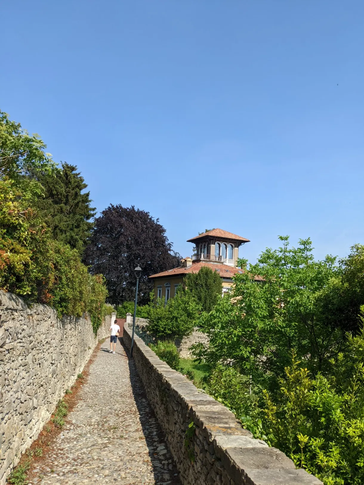 Sentier pavé entre deux murs menant vers une villa