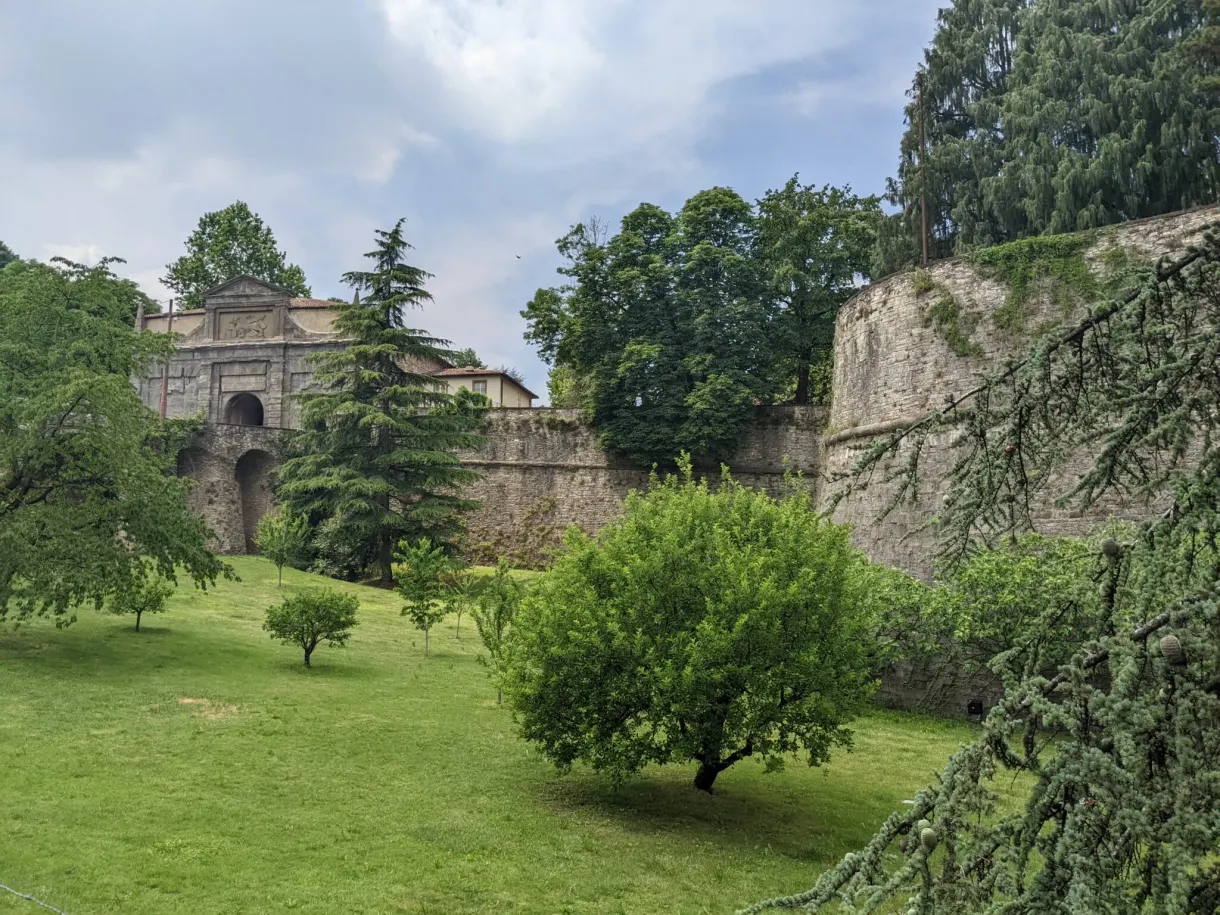 Porte fortifiée au bout d'une pelouse plantée d'arbres