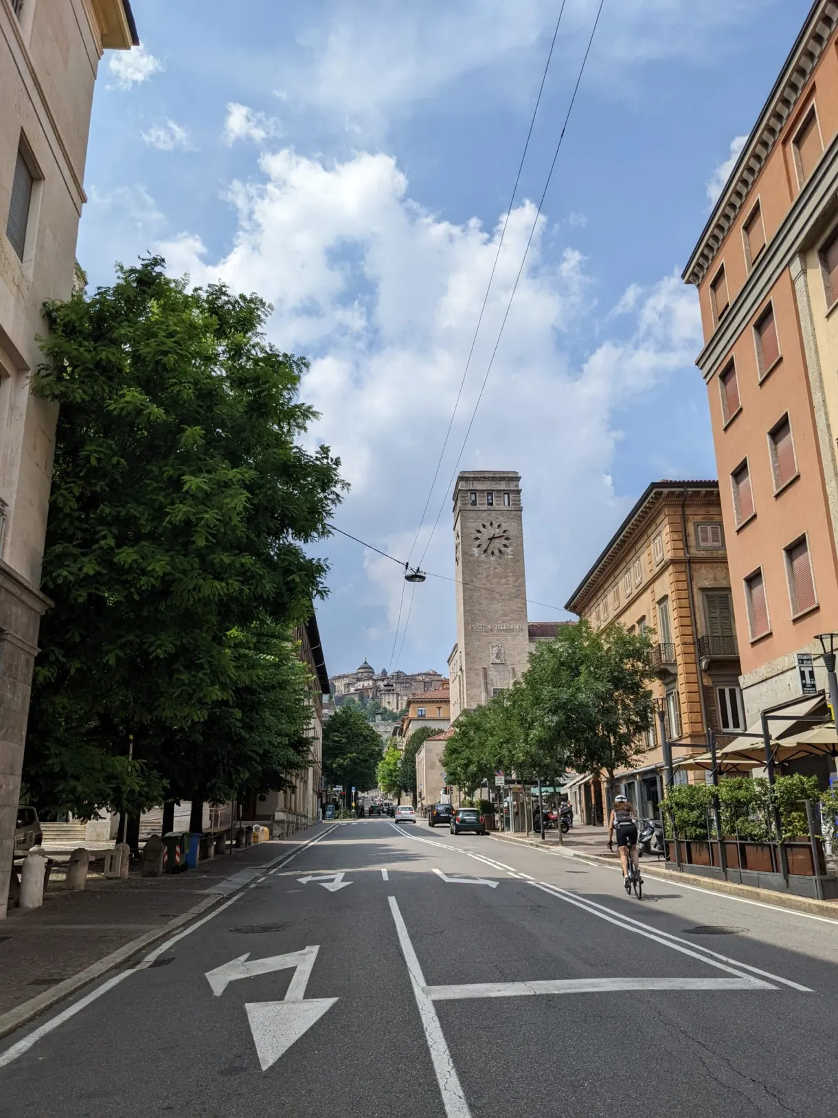 Avenue rectiligne fermée au loin par une tour d'horloge