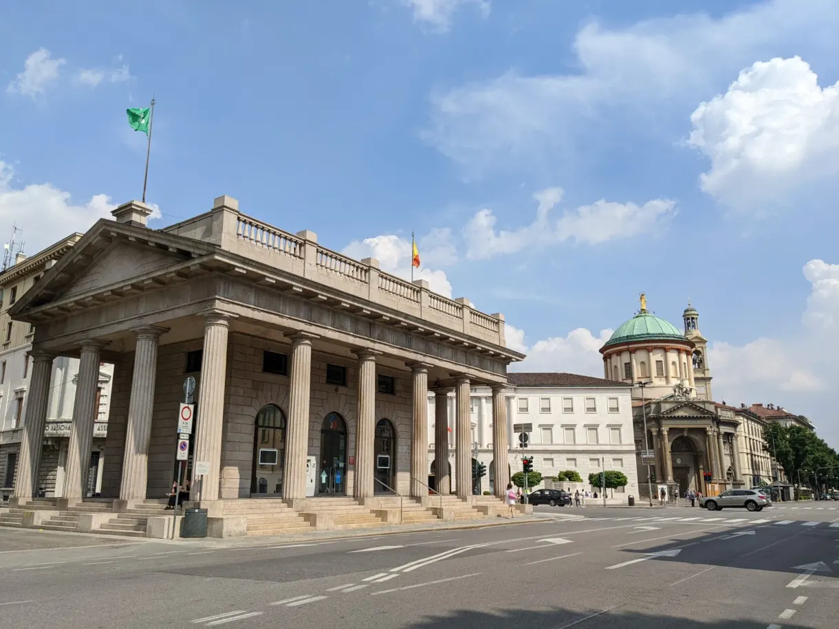 Colonnade néoclassique et coupole verte au bout d'une rue déserte