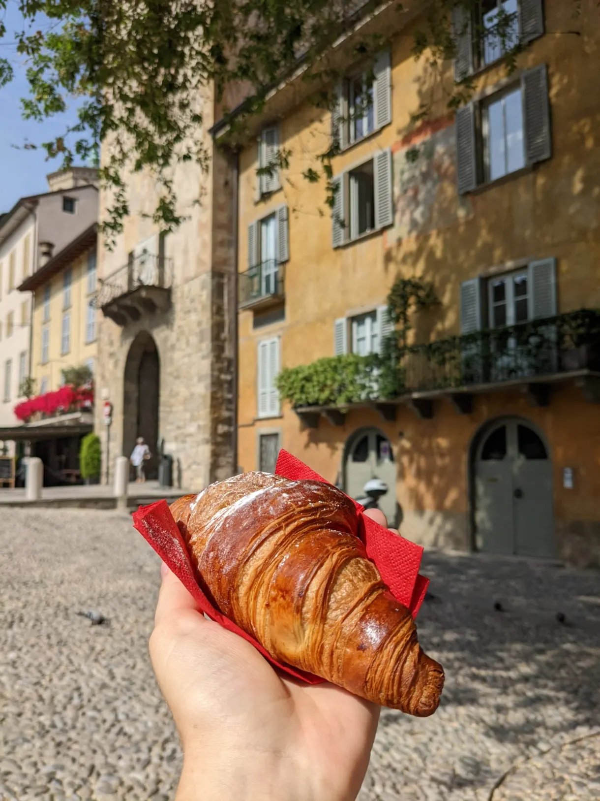 Croissant tenu à la main devant une façade ocre