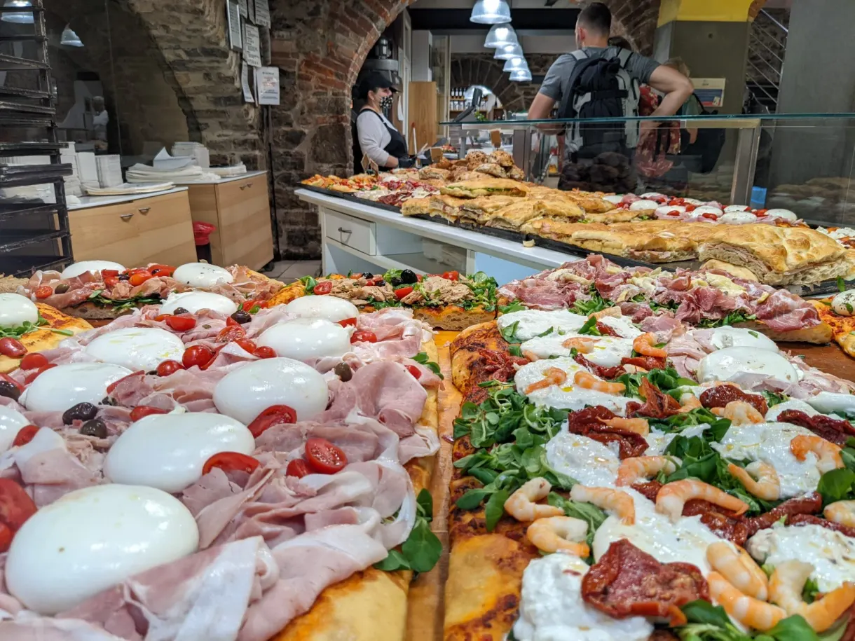 Étal de parts de focaccia garnies derrière une vitrine