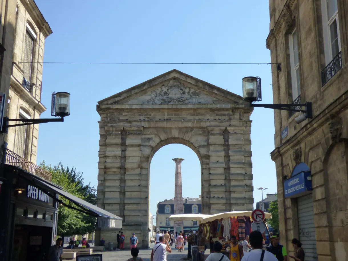 Arc monumental à fronton triangulaire ouvrant sur une place animée