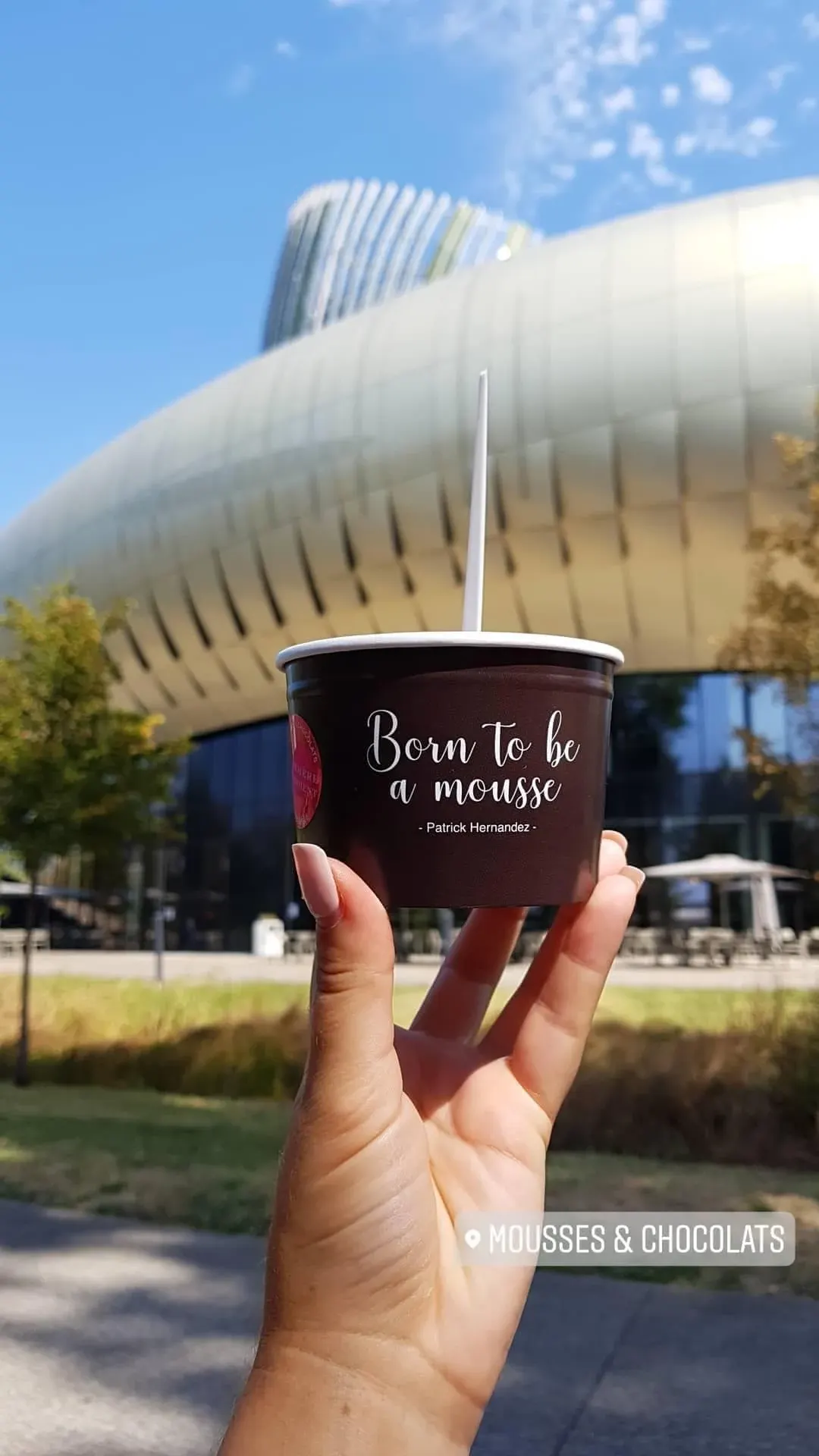 Gobelet de mousse au chocolat tenu à bout de bras devant la Cité du Vin