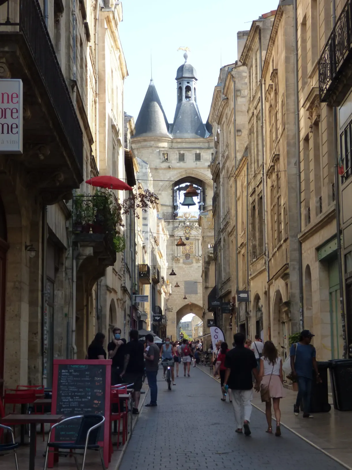 Terrasse aux chaises rouges dans une rue piétonne menant au beffroi