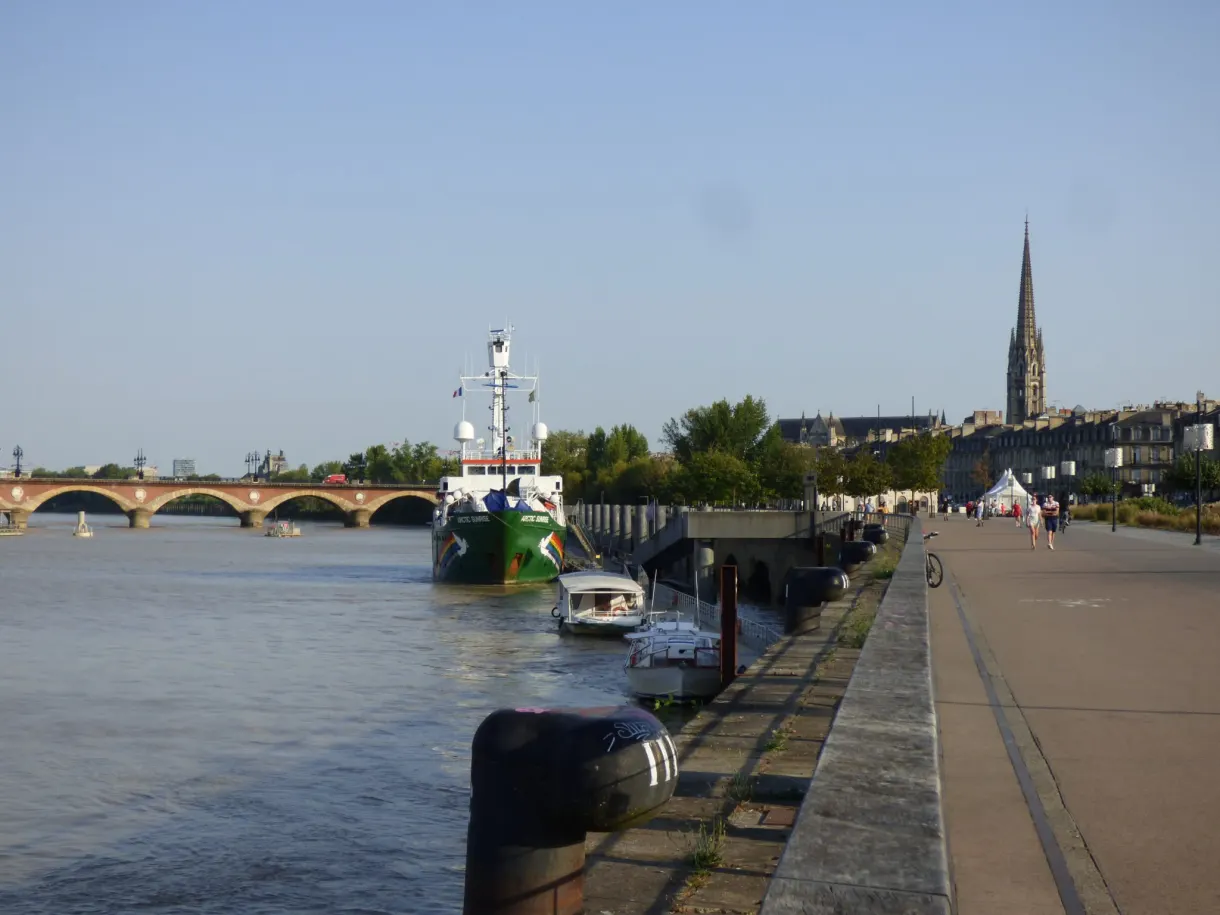 Quai au bord de la Garonne, péniche amarrée et pont en arches au loin