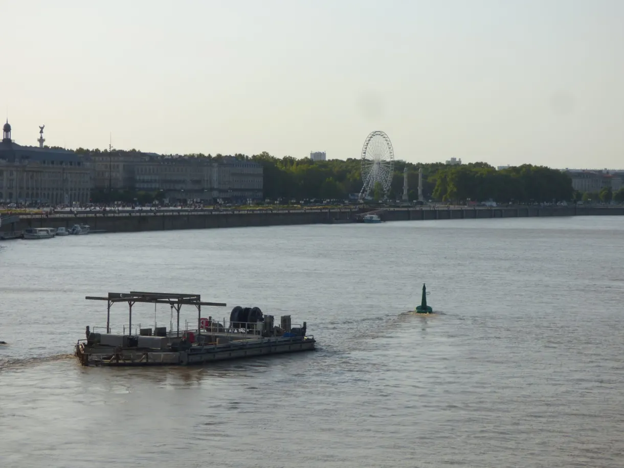 Barge remontant le fleuve brun devant une grande roue