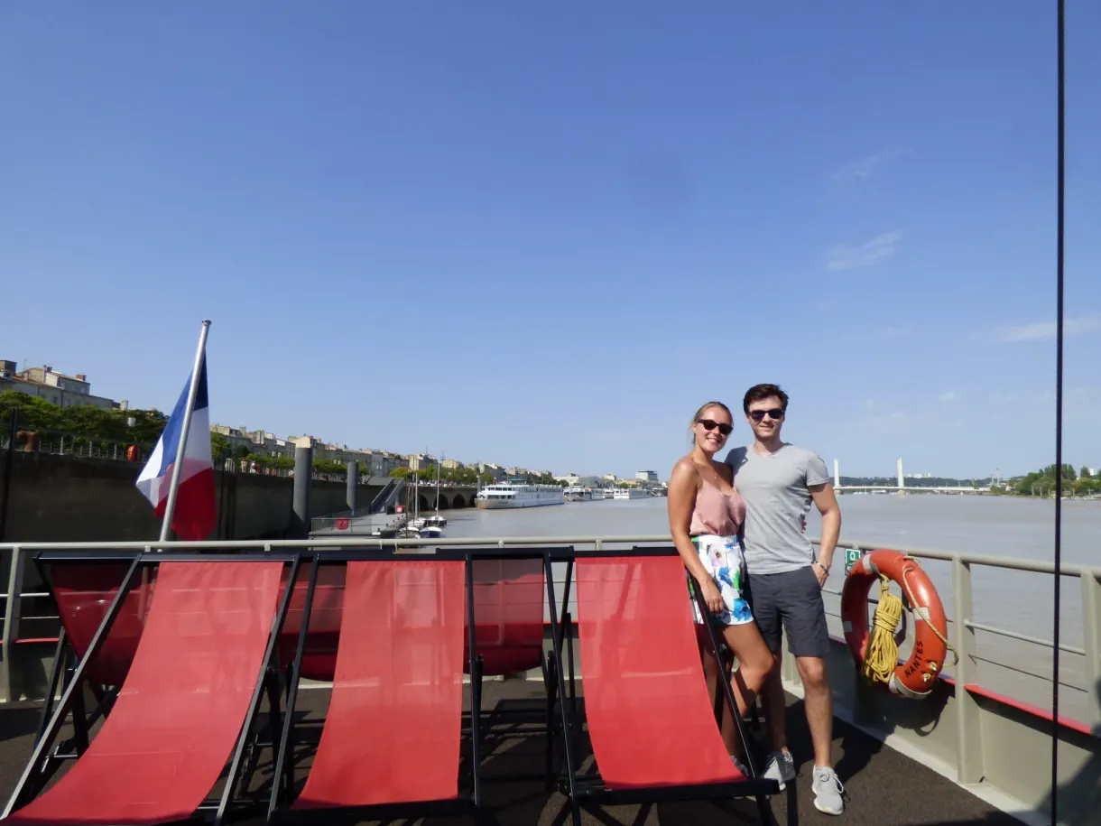Couple posant sur le pont d'un bateau aux transats rouges