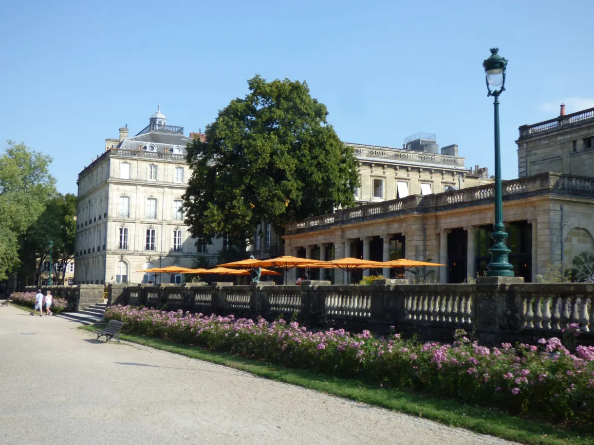 Massifs de fleurs devant un pavillon néoclassique et ses parasols