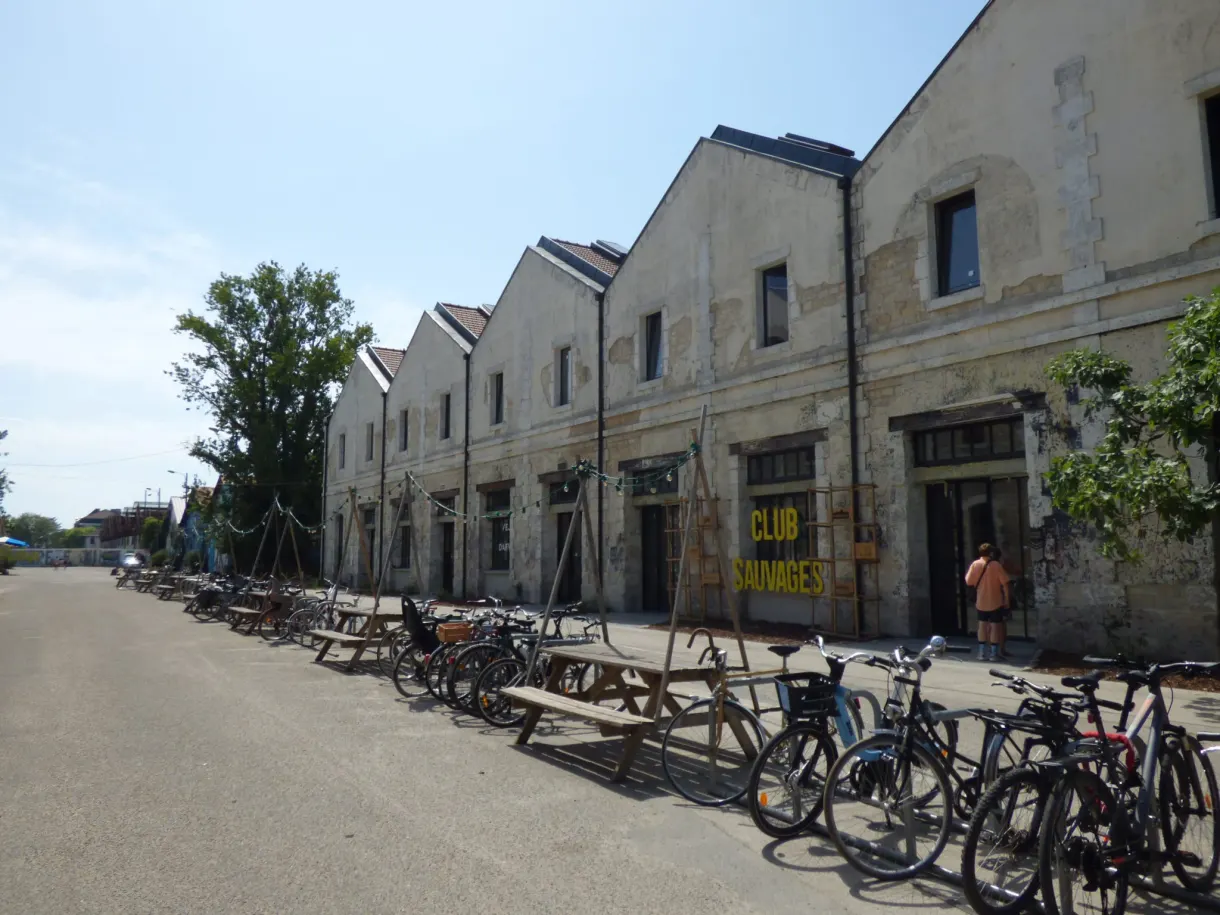 Vélos alignés devant une enfilade de hangars en pierre réhabilités