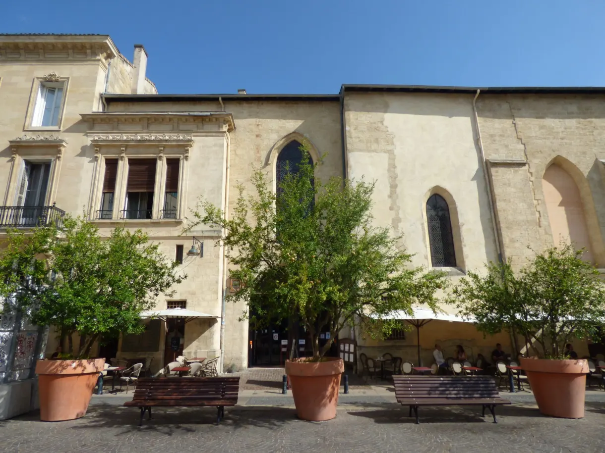 Placette arborée aux pots de terre cuite devant une église de pierre