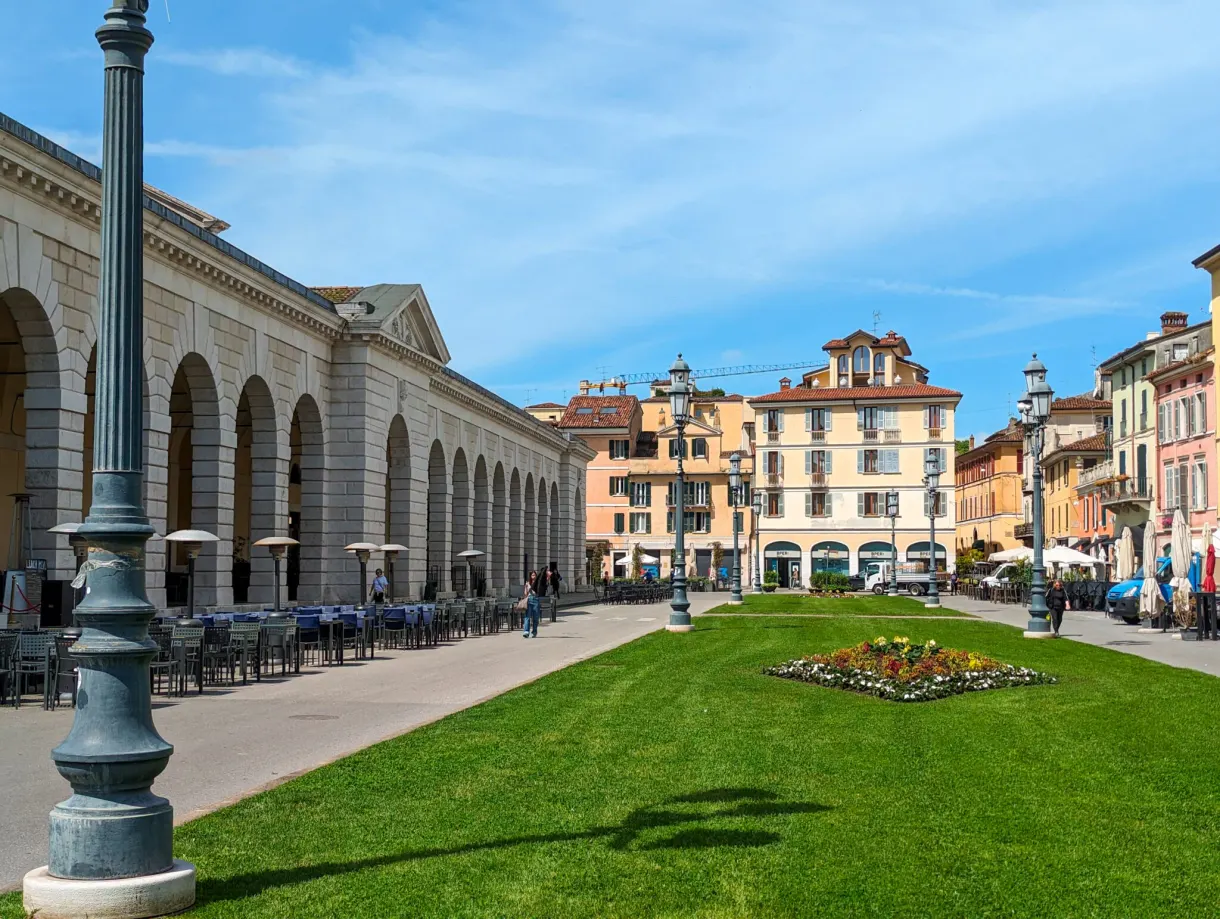 Longue colonnade bordant une place au gazon fleuri