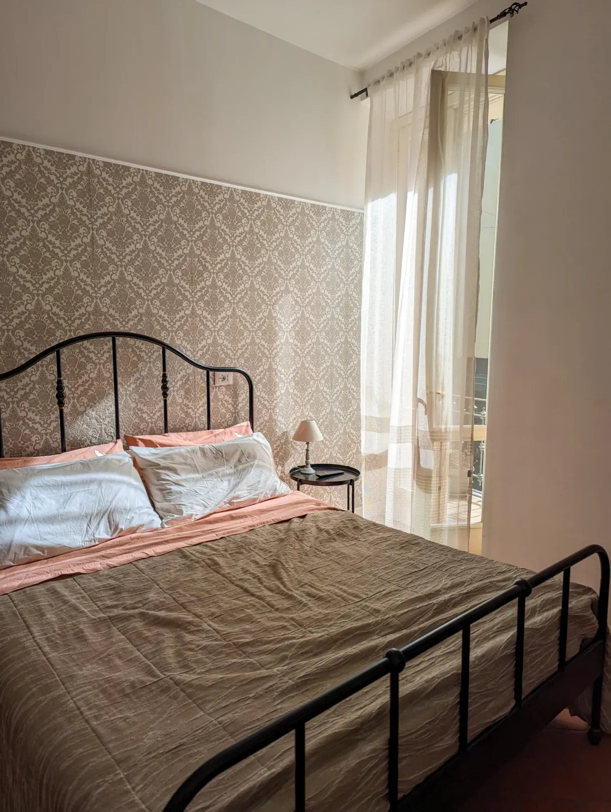 Lit en fer forgé et rideaux clairs dans la chambre louée
