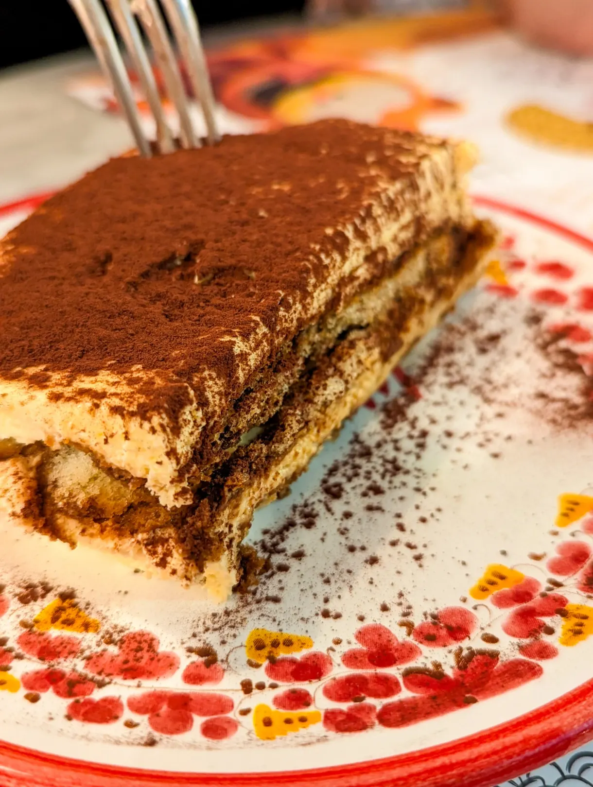 Part de tiramisu poudrée de cacao sur une assiette décorée