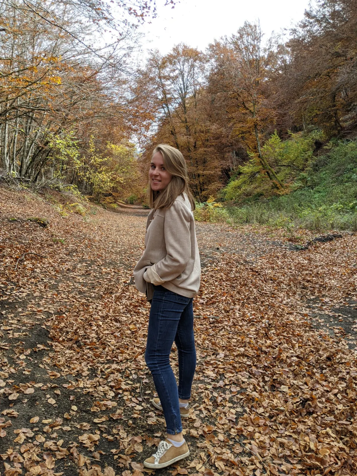 Randonneuse s'arrêtant sur un tapis de feuilles rousses