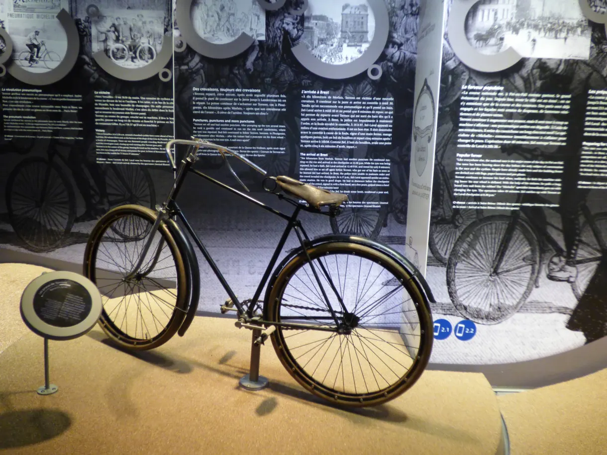 Bicyclette ancienne exposée devant des panneaux d'histoire