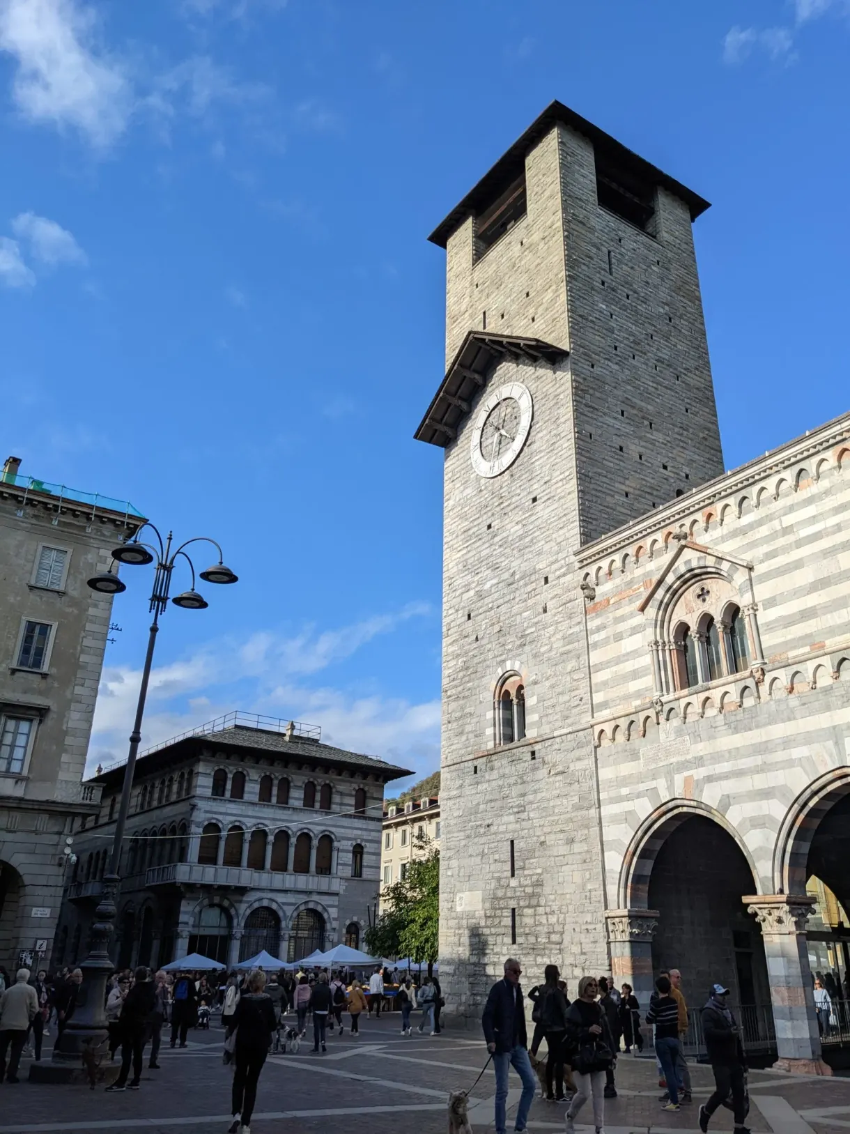 Tour de l'horloge en pierre dominant une place animée