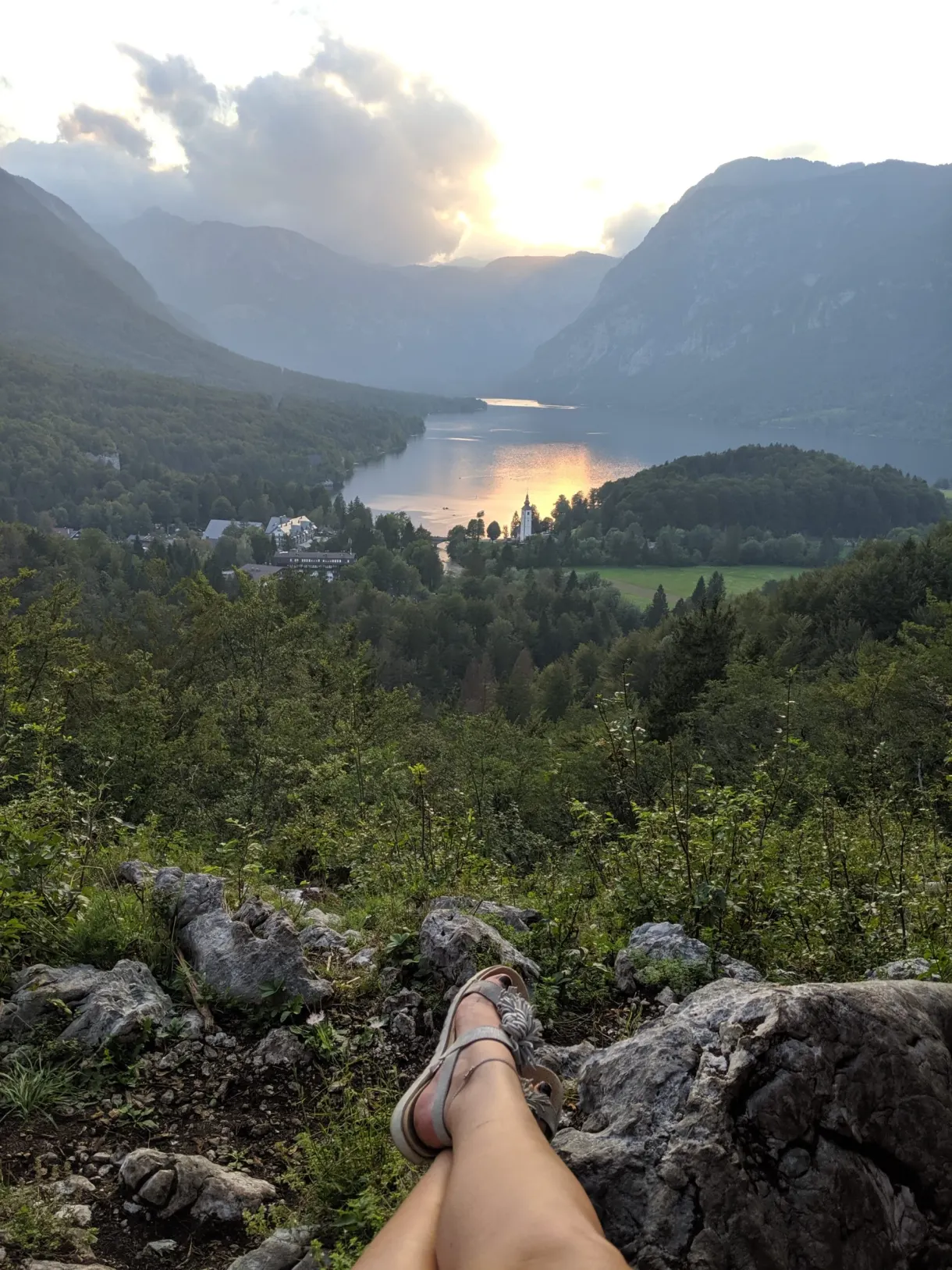 Jambes posées sur un rocher face au lac en contrebas