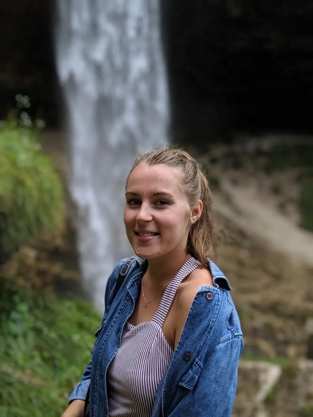 Jeune femme souriante devant le rideau de la cascade